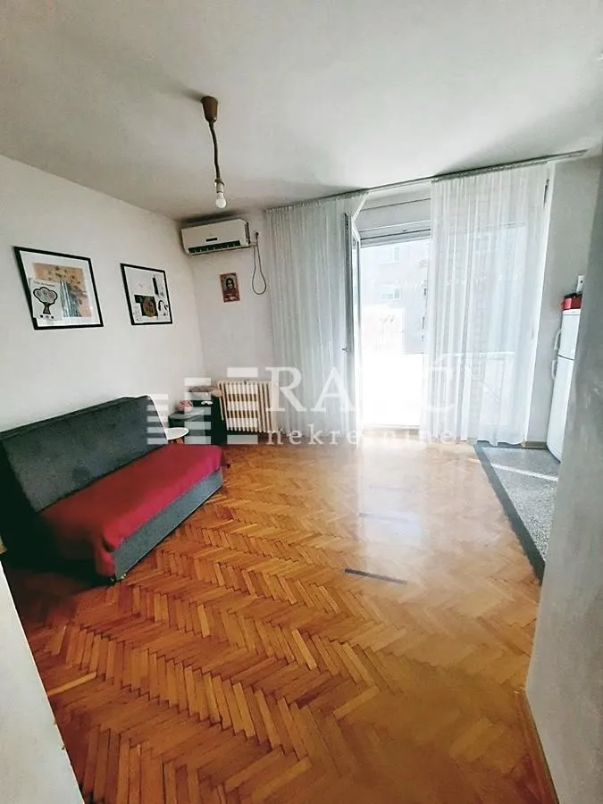Living room with parquet flooring and a sofa.