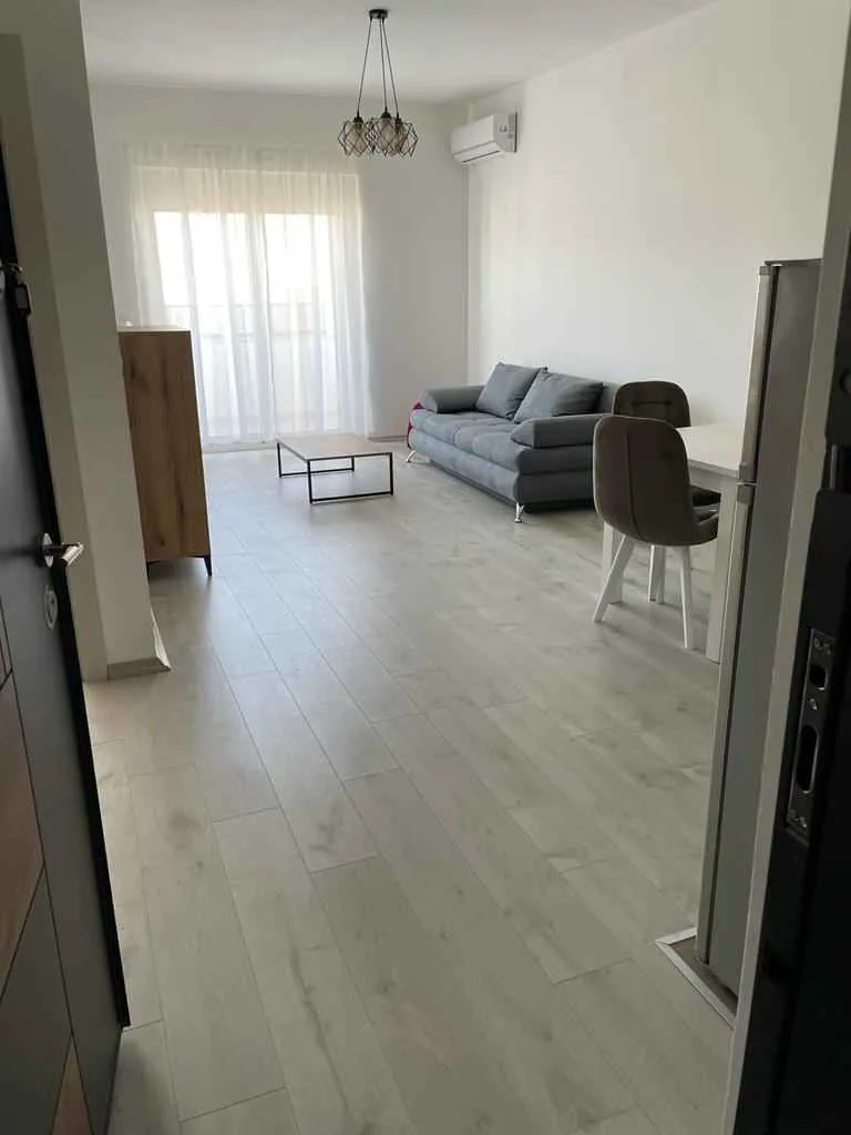Svijetla dnevna soba sa sivom garniturom i trpezarijskim stolom.