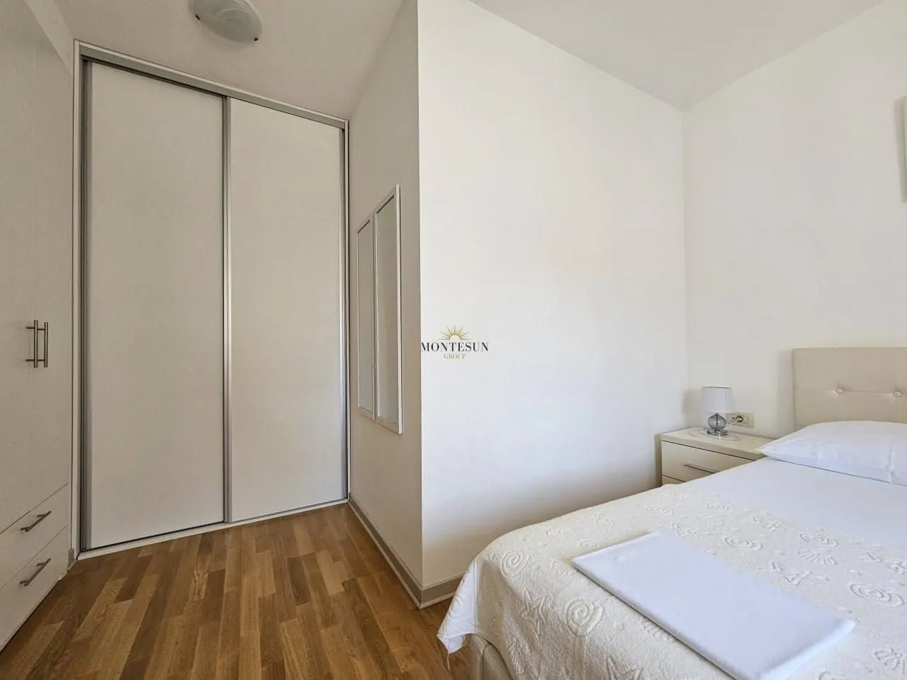 Bright bedroom with a double bed, built-in wardrobe, and wooden flooring.