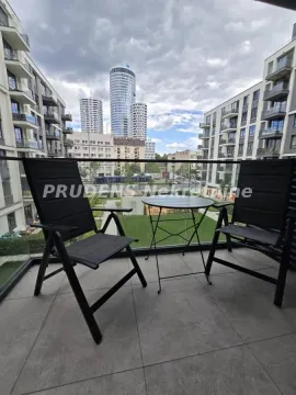 Namešten balkon sa stolom i dve stolice i pogledom na okolne zgrade. - image 7