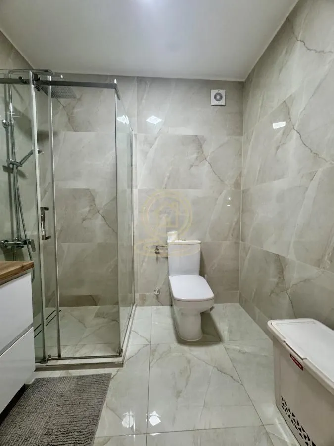 Modernly equipped bathroom with a walk-in shower and marble-style tiles.