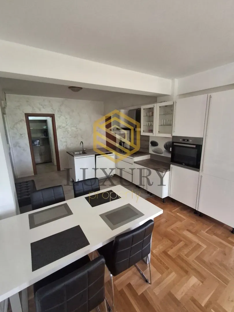 Dining area connected to the kitchen with white cabinetry and hardwood flooring.