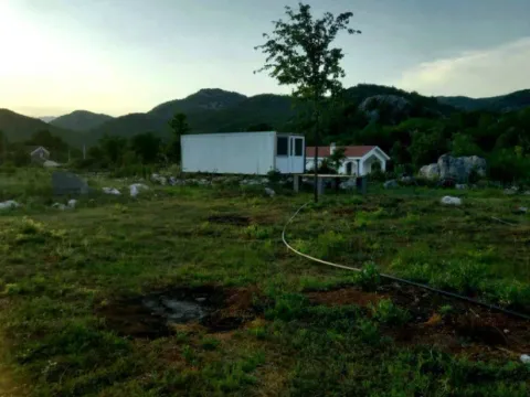 Pogled na plac sa manjim montažnim objektom i brdima u pozadini. - image 3