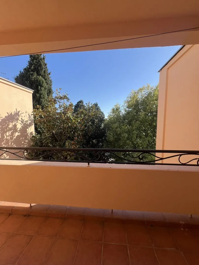 Balcony with tiled floor and a view of surrounding greenery.