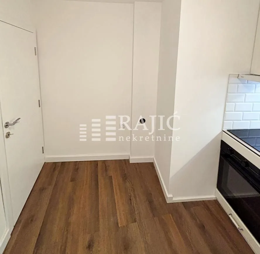 View of a section of the kitchen with built-in appliances and hardwood flooring.