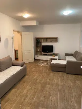Dnevna soba sa garniturom za sedenje, televizorom i drvenim podom. - image 2