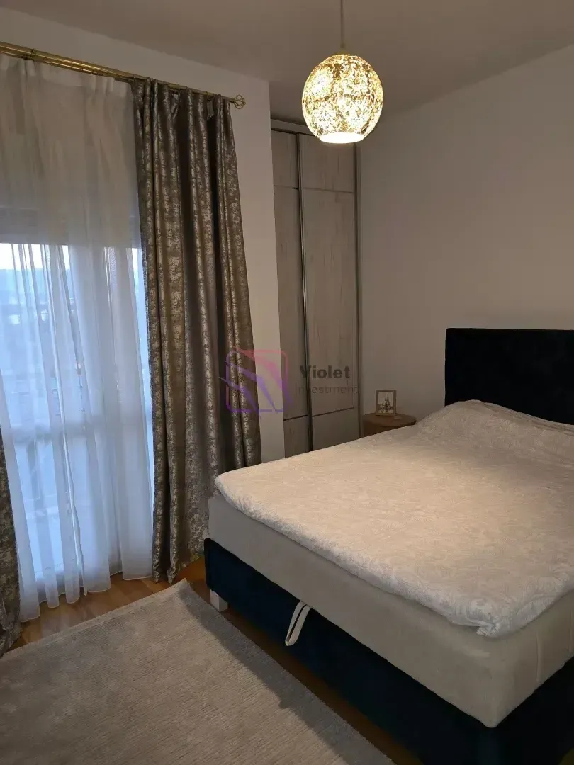 Furnished bedroom with a double bed, wardrobe, and a window with curtains.