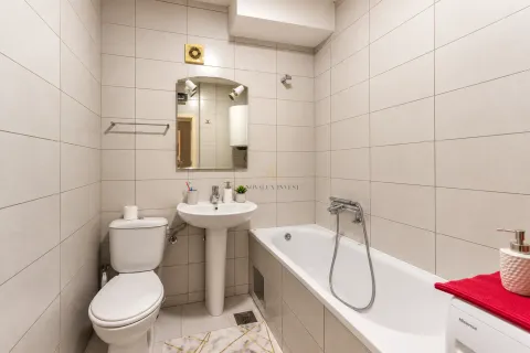Kompaktno kupatilo sa kadom, umivaonikom i wc šoljom obloženo svijetlim pločicama. - image 8