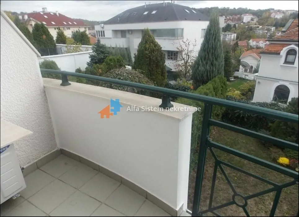 Balcony with railing and a view of the neighborhood and greenery.