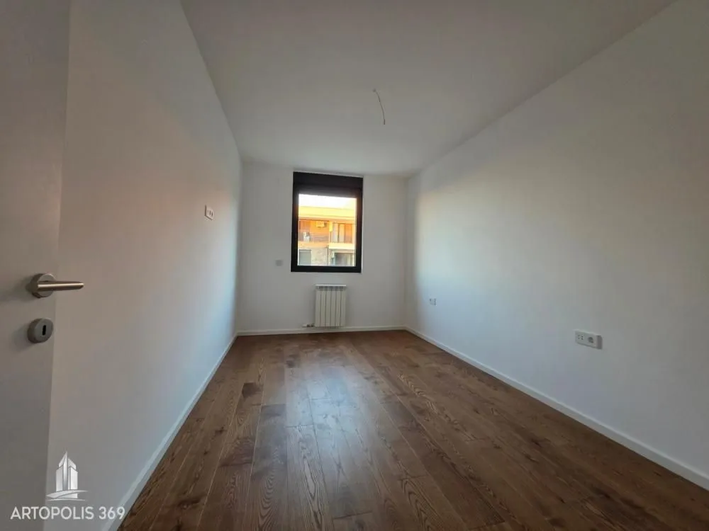 Prazna soba sa drvenim podom i prozorom.