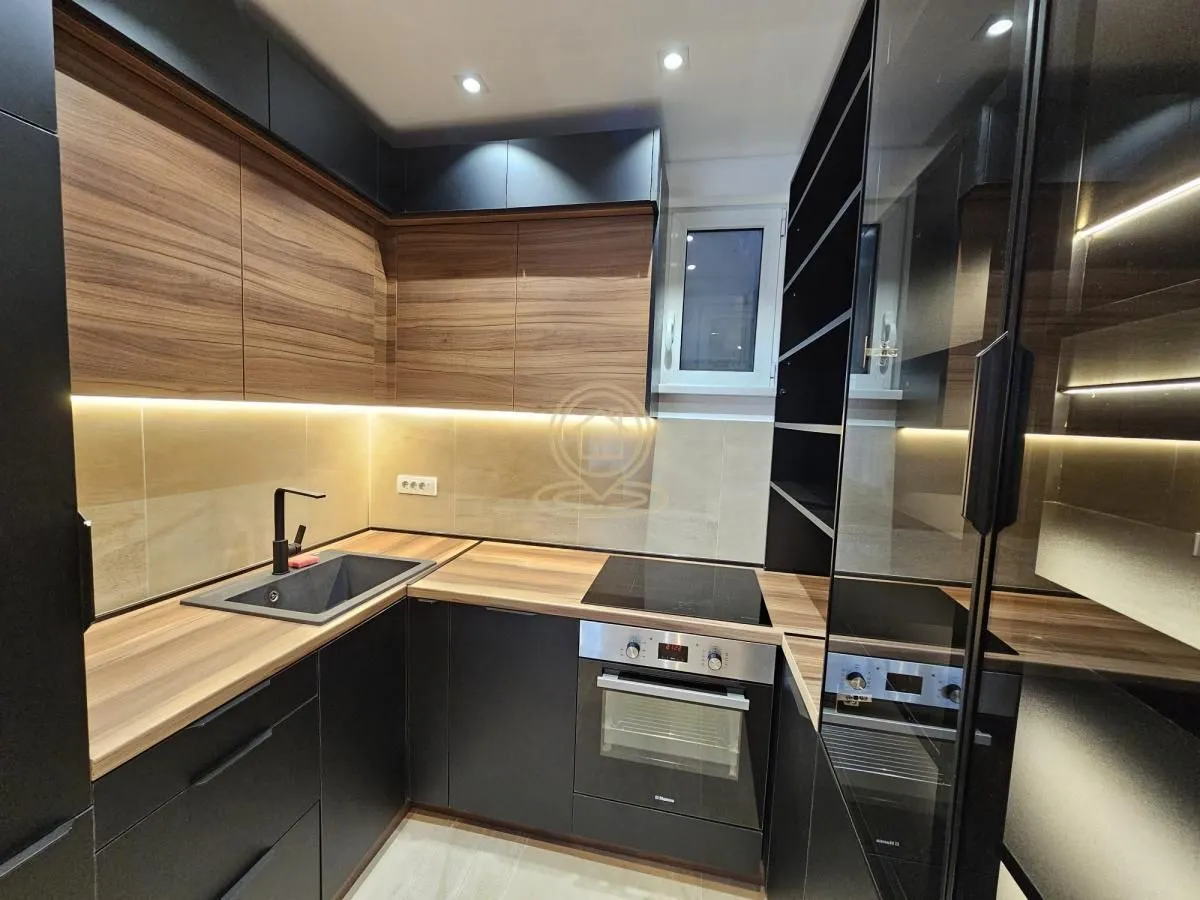 Modern kitchen with dark cabinets and wood-grain countertops.