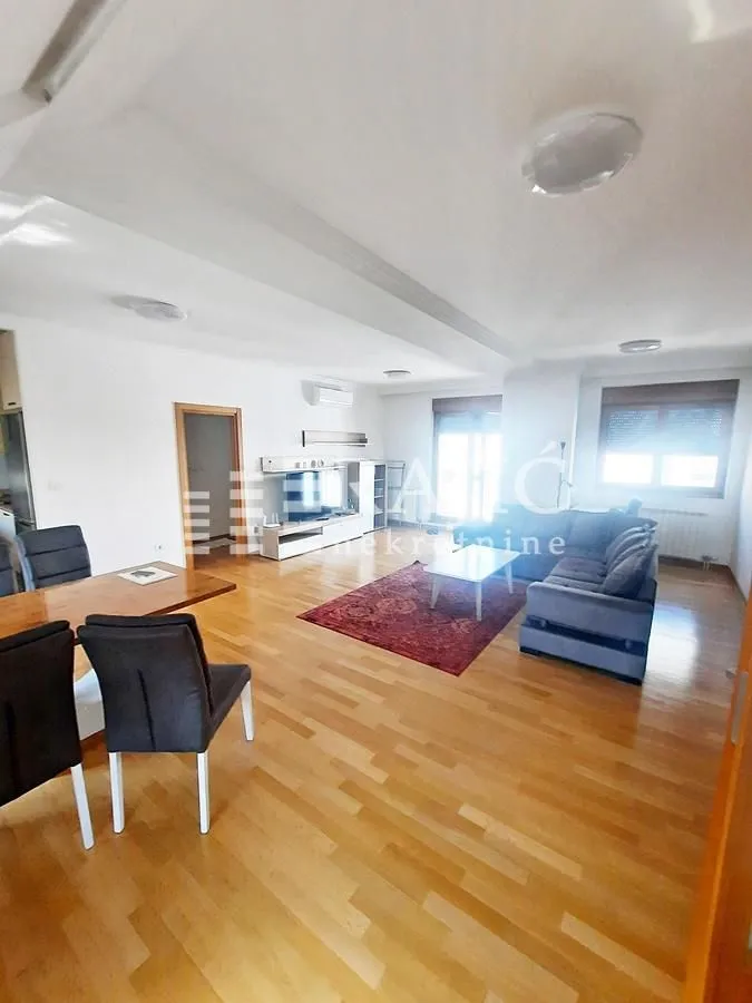 Spacious living room with dining area and parquet flooring.