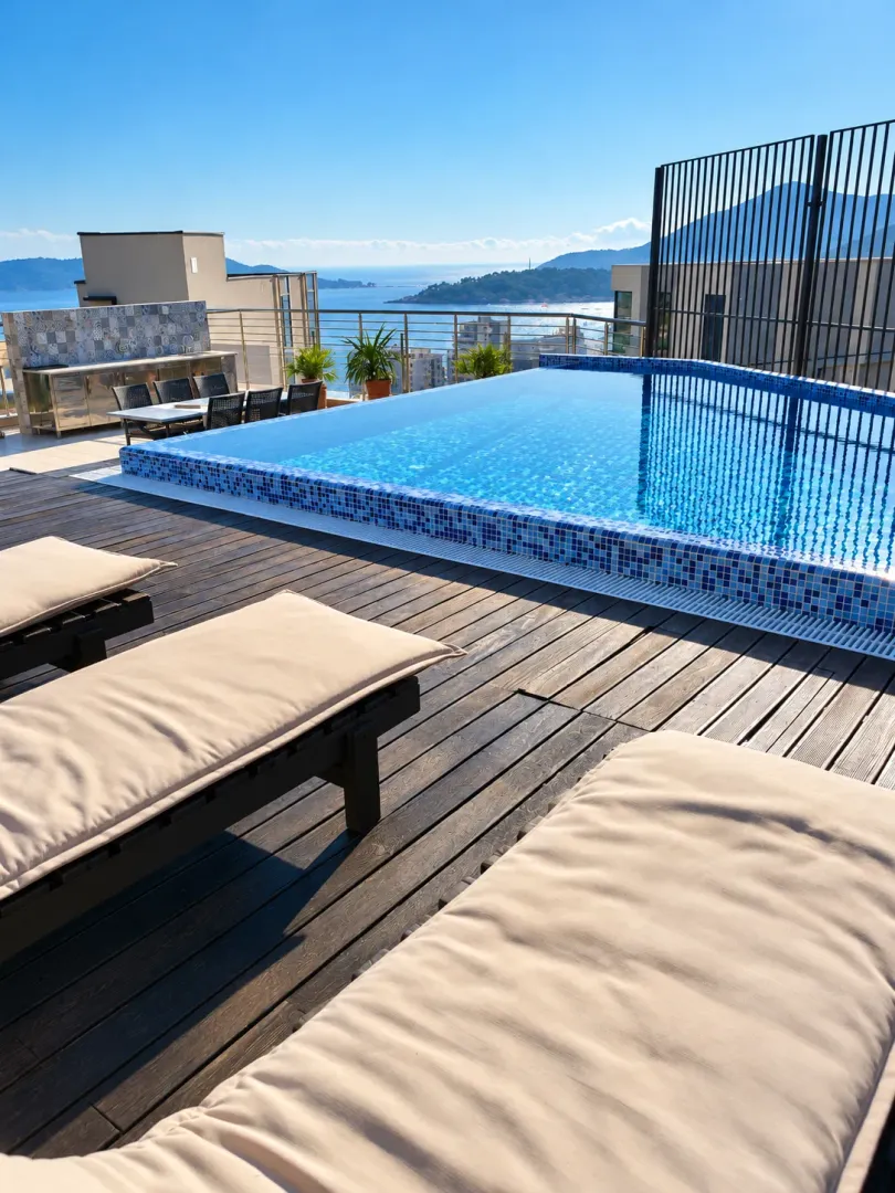 Rooftop terrace with a swimming pool, sun loungers, and a sea view.
