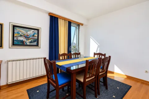 Trpezarija sa drvenim stolom i stolicama, prozorom i umjetničkom slikom na zidu. - image 6