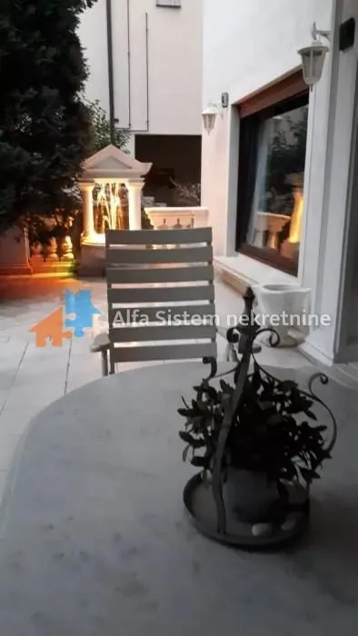 Yard with a table and chairs in front of the house at dusk.