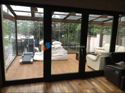 Enclosed glass terrace with wooden flooring, seating furniture, and exercise equipment. - image 34