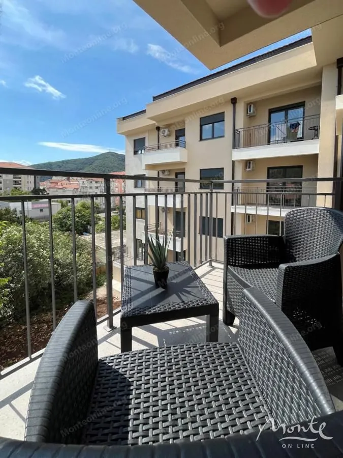 Namješten balkon sa garniturom za sjedenje i pogledom na okolne zgrade i brda.