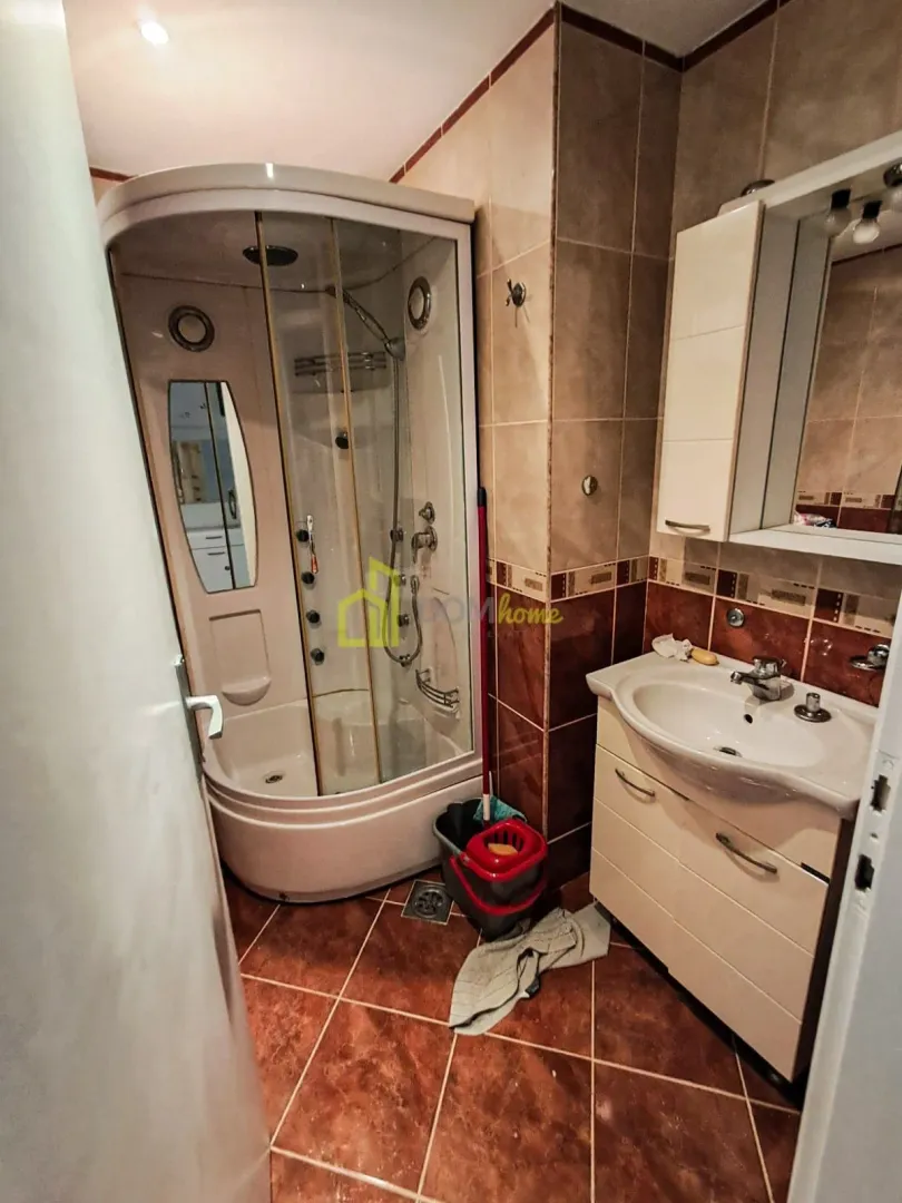 Bathroom with a shower cabin, vanity unit with sink, and wall-mounted mirror cabinet.