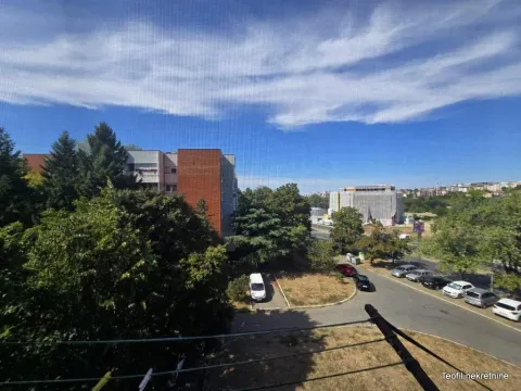Pogled sa prozora na okolne zgrade, zelenilo i parking. - image 9