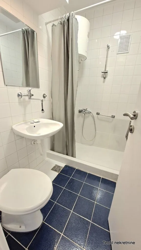 Smaller bathroom with a shower cabin, washbasin, and toilet.