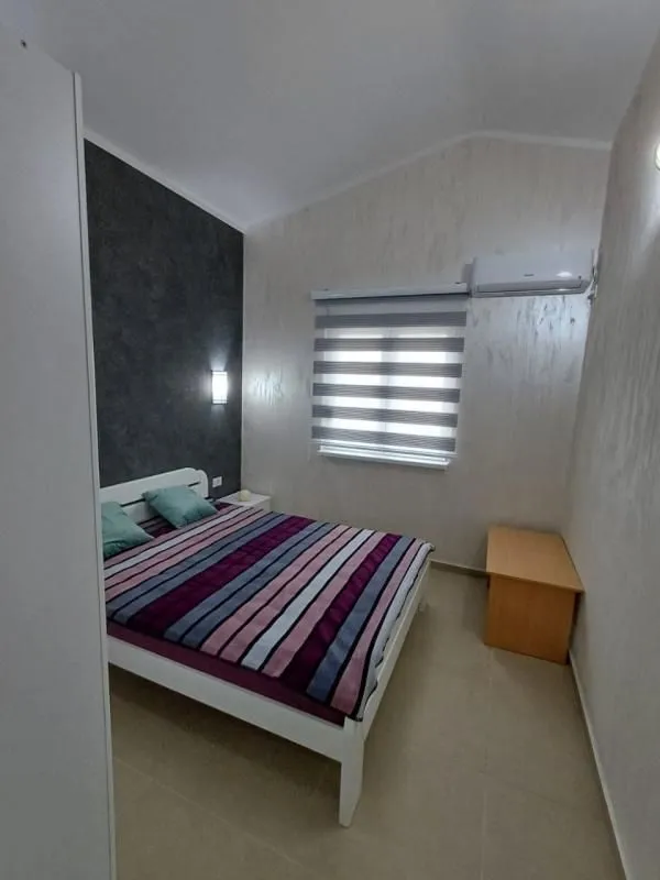Bedroom with a double bed, window, and air conditioning unit.