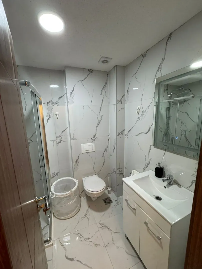 Modernly equipped bathroom with a shower cabin and marble tiles.