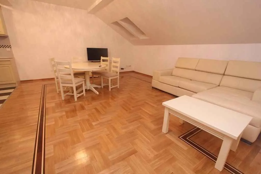 Svijetla dnevna soba sa trpezarijskim stolom i kožnom garniturom.