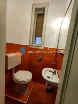 Small bathroom with a toilet, washbasin, and orange tiles. - image 14
