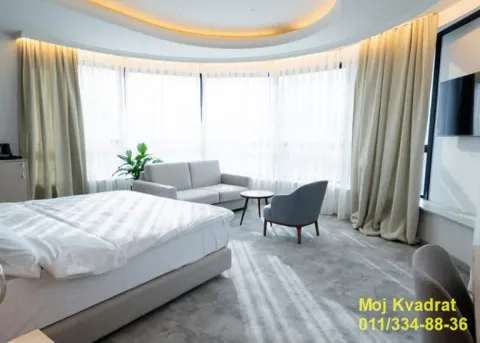 Spacious bedroom with a double bed, seating area and large windows. - image 5