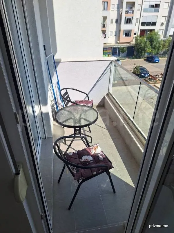 Smaller furnished balcony with a table and chairs and a view of surrounding buildings.