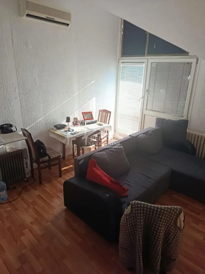 Dnevni boravak sa ugaonom garniturom, trpezarijskim stolom i izlazom na terasu.