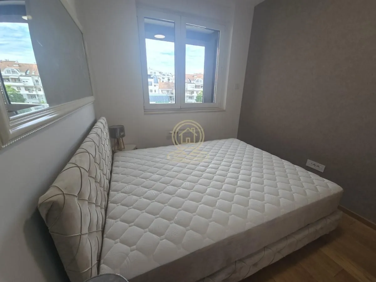 Spavaća soba sa bračnim krevetom i prozorom koji gleda na grad.
