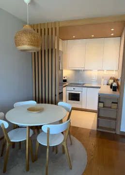 Modern kitchen with a dining area and white cabinets. - image 6