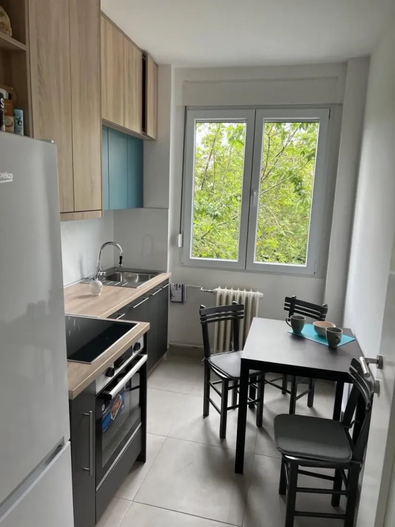 Small kitchen with a dining table and a window overlooking greenery.