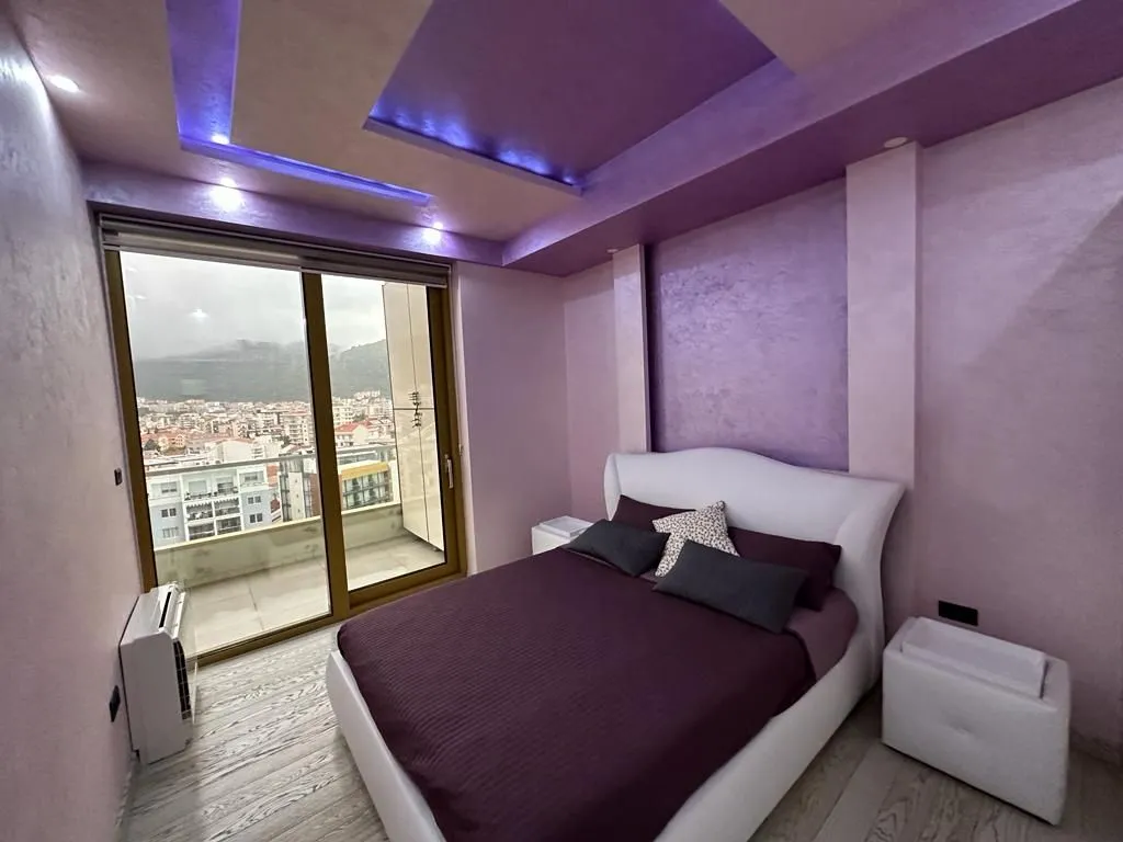 Modern bedroom with a double bed, purple walls, and balcony access.