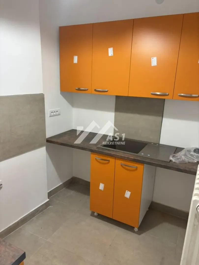 Small kitchen with orange cabinets and a sink.