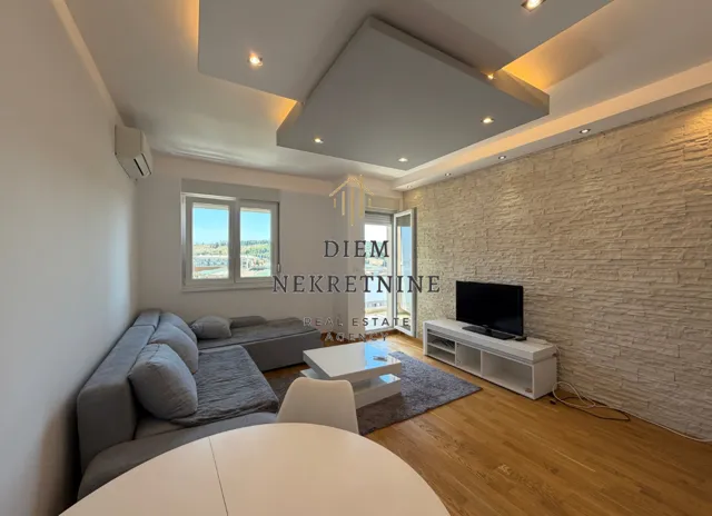 Dnevna soba sa garniturom, TV komodom i modernim spuštenim plafonom.