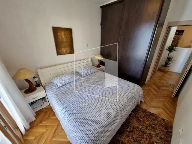 Furnished bedroom with a double bed, wardrobe, and parquet flooring.