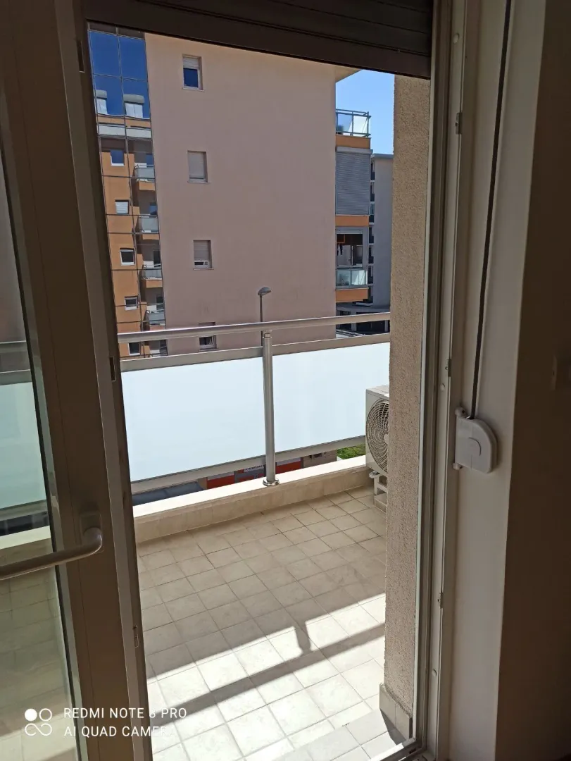 Balkon stana sa ogradom slikan kroz otvorena vrata.