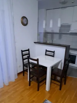 Trpezarijski sto sa stolicama i kuhinja u pozadini. - image 4