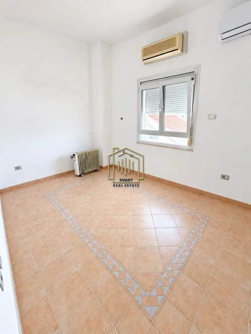 Empty bright room with tiled flooring, a window, and an air conditioning unit.