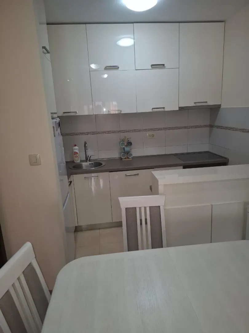 Smaller kitchen with white cabinetry and a dining table in the foreground.