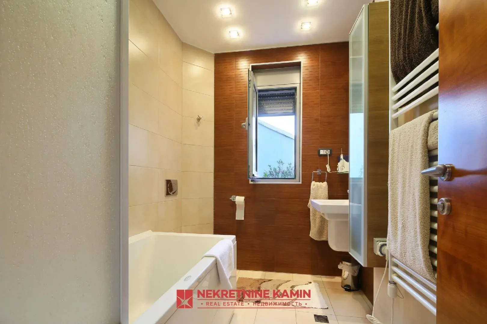 Bathroom with a bathtub, washbasin, and wooden wall paneling.