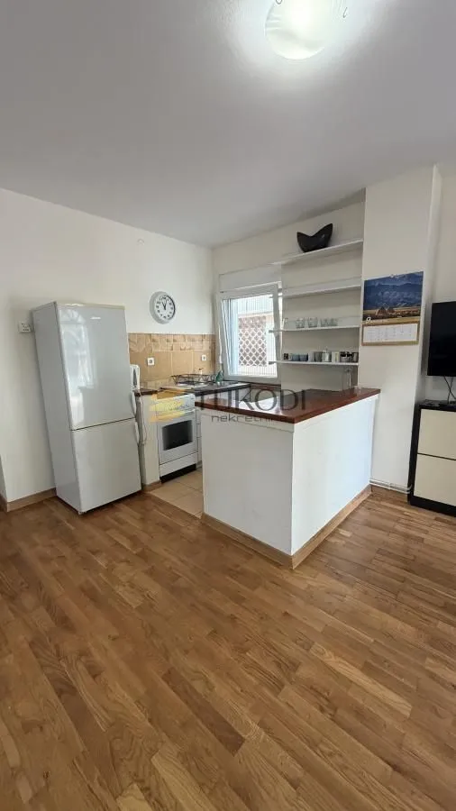 Small kitchen with a breakfast bar, refrigerator, and wooden floor.