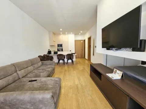 Living room with a sofa and television, overlooking the kitchen in the background. - image 3
