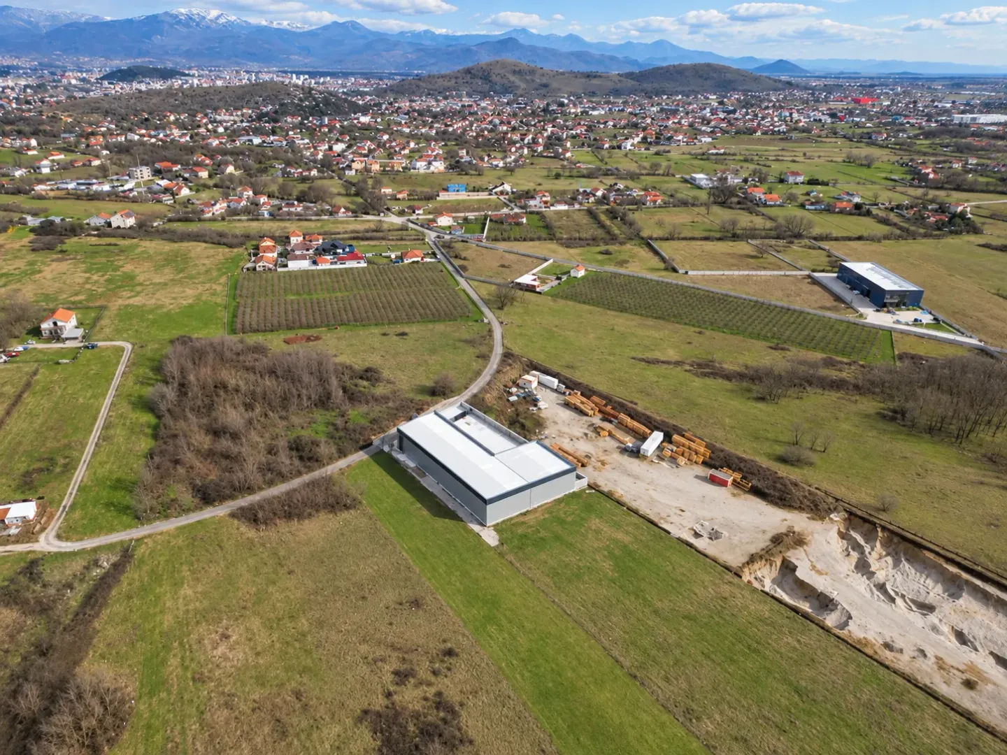 Aerial view of an industrial building under construction surrounded by nature and fields.