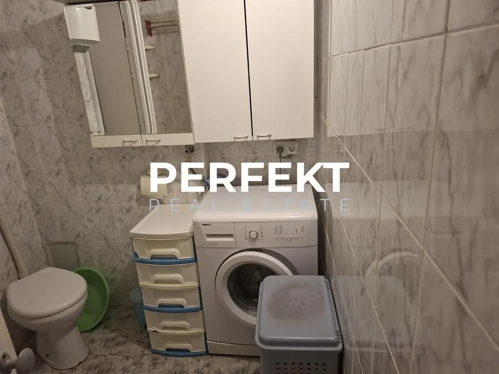 Manje kupatilo sa sanitarijama, mašinom za veš i zidnim elementima.