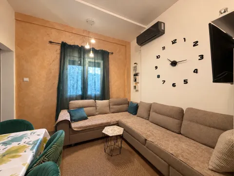 Living room with a sectional sofa, dining table, and wall clock. - image 3