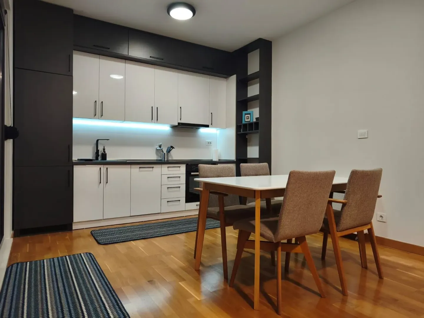 Kitchen with a dining area and modern white and black cabinetry.