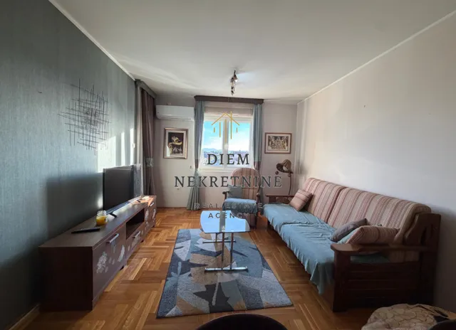 Dnevna soba sa garniturom, televizorom i parketom.